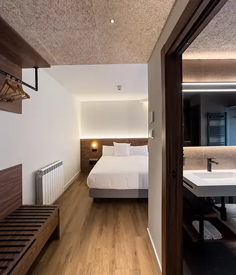 Habitaci&oacute;n de Biazteri con cabecero de madera y textiles en tonos burdeos